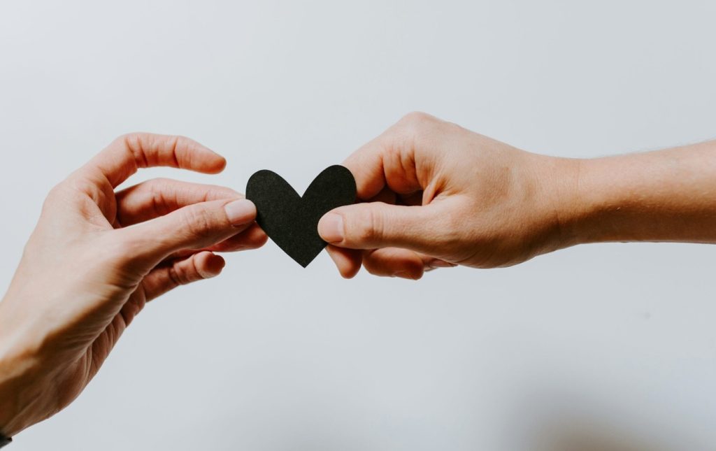 Picture of two hands gently holding a paper heart