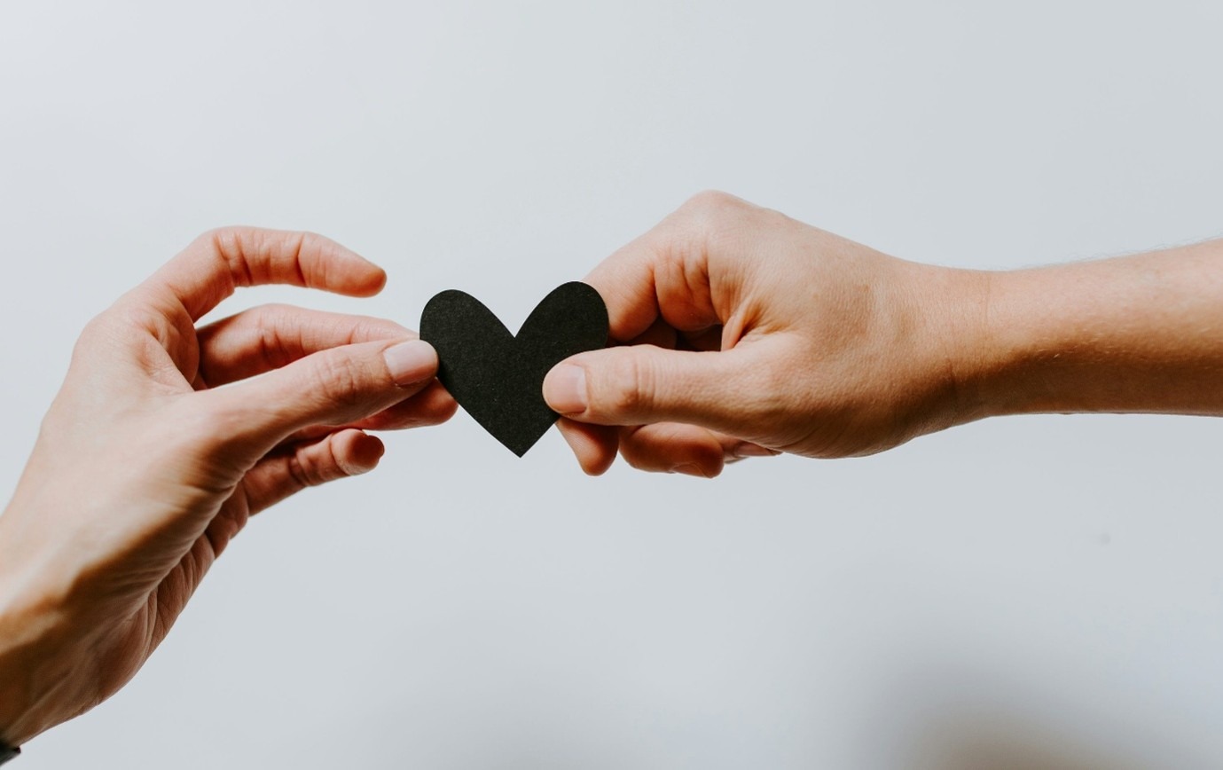 Picture of two hands gently holding a paper heart